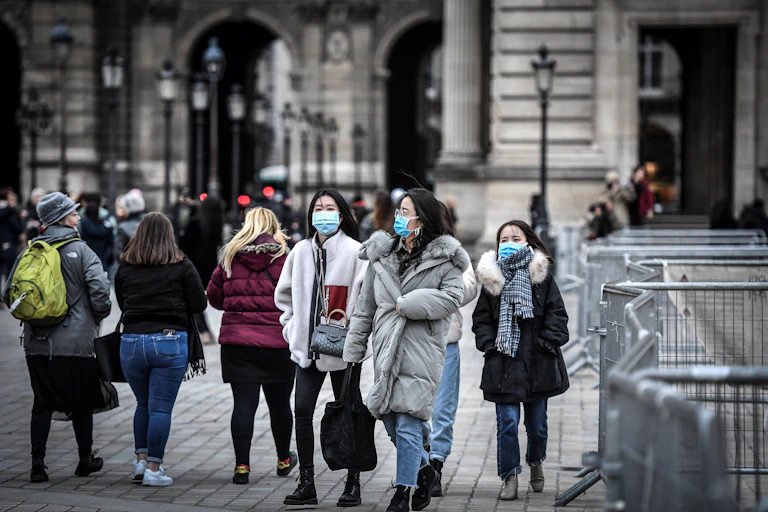 Photo de touristes au Louvres, dont certains sont masqués.