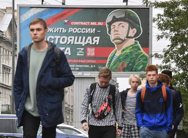 Des passants marchent devant un panneau promouvant le service militaire contractuel avec le slogan « Servir la Russie est un vrai travail », à Saint-Pétersbourg, le 29 septembre 2022.