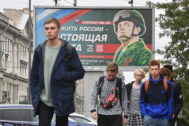 Des passants marchent devant un panneau promouvant le service militaire contractuel avec le slogan « Servir la Russie est un vrai travail », à Saint-Pétersbourg, le 29 septembre 2022.