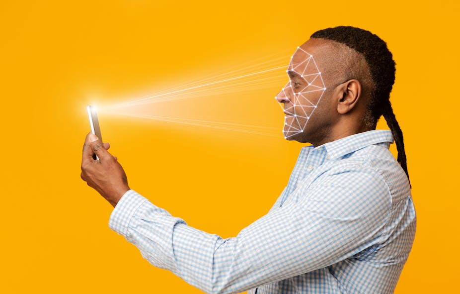 A Black man scanning his face with a phone.