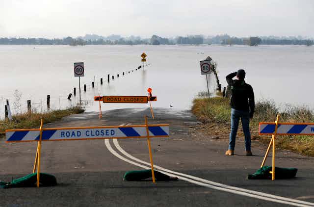 A man looks at a flooded road