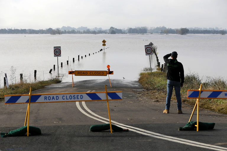A man looks at a flooded road