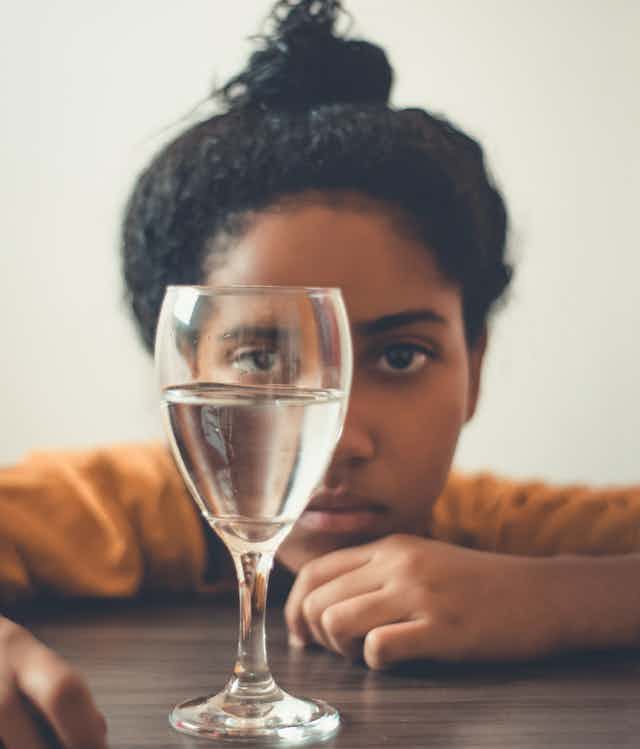 girl stares into glass of water