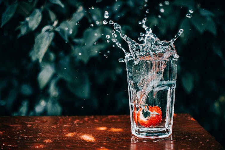 strawberry splashes into glass of water