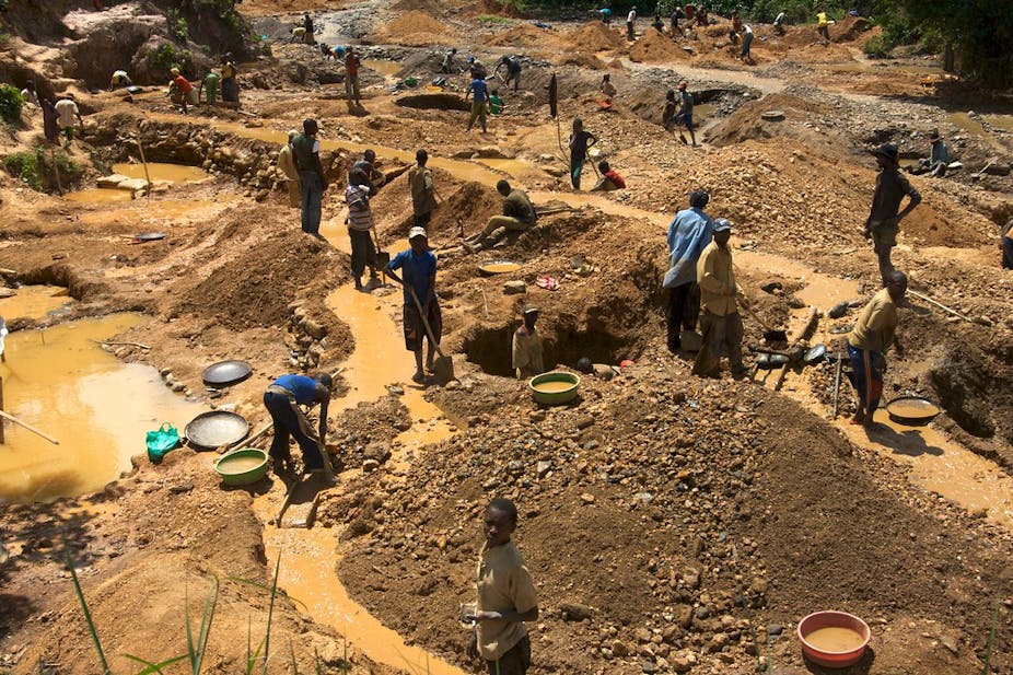 Men and women spread around a piece of land mining gold