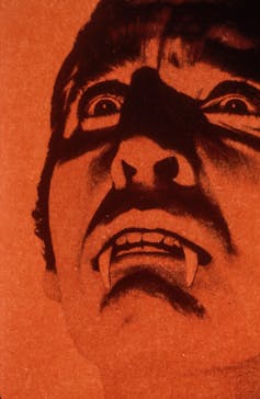 A red and black shadowy picture of Christopher Lee as Dracula.