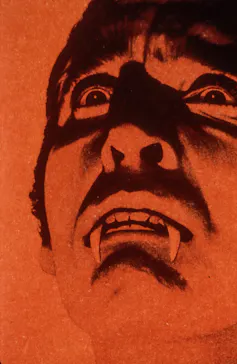 A red and black shadowy picture of Christopher Lee as Dracula.