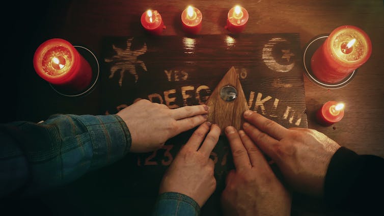 Two people use a Ouija board together.