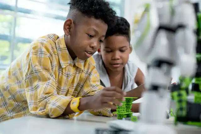 Two children stack plastic shapes on a table