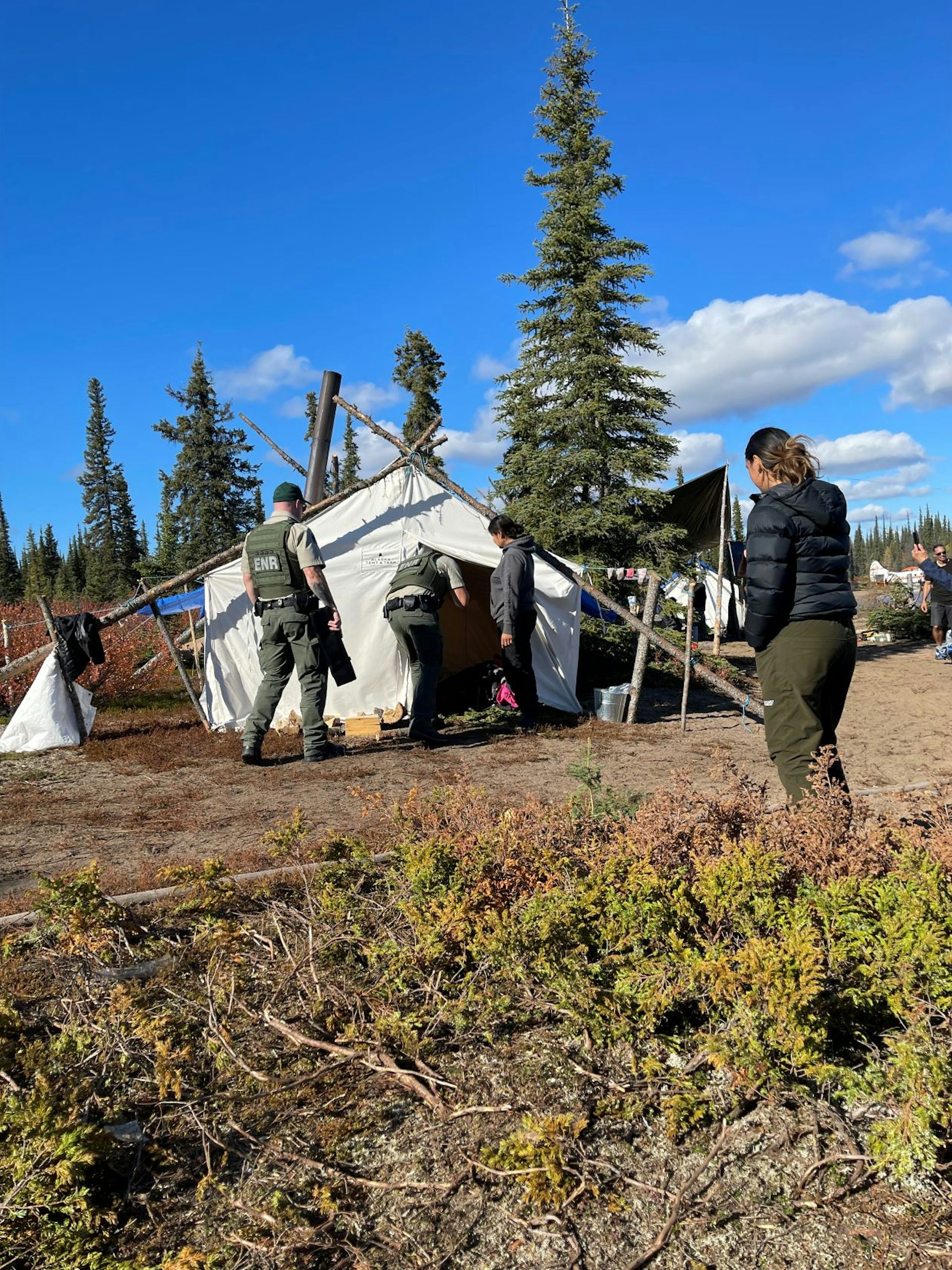 Two wildlife officers enter a tent