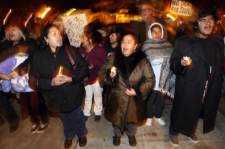 In a crowded scene, people chant and hold protest signs.
