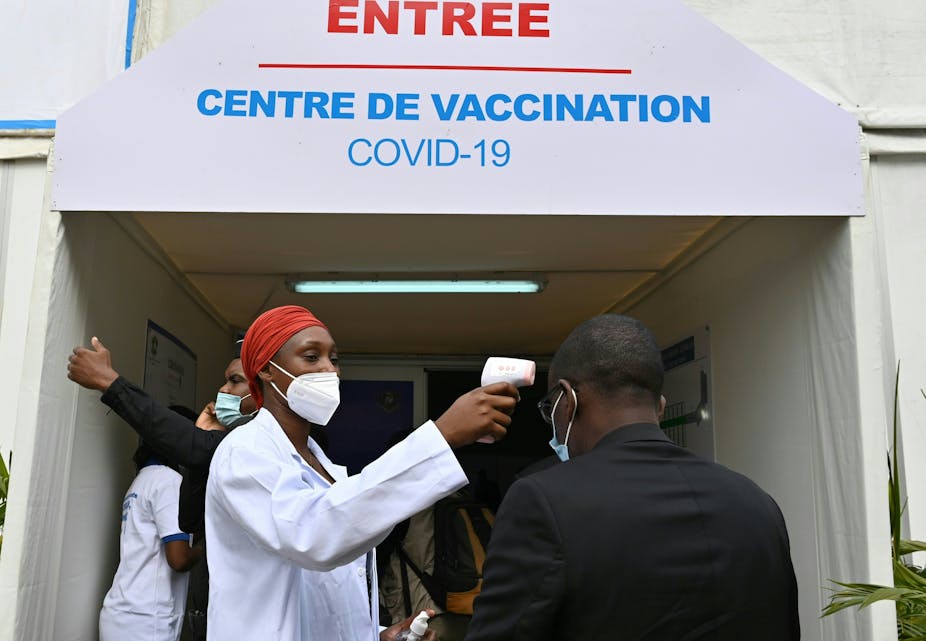 Un homme se fait prendre la température avant d’entrer dans un centre de vaccination pour recevoir une dose de vaccin anti-Covid-19, à Abidjan, en Côte d’Ivoire.