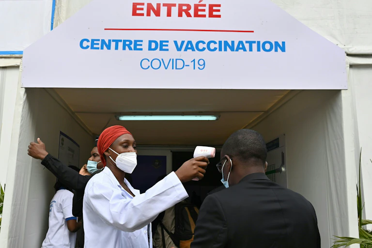 Un homme se fait prendre la température avant d’entrer dans un centre de vaccination pour recevoir une dose de vaccin anti-Covid-19, à Abidjan, en Côte d’Ivoire.