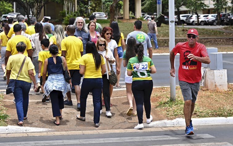 Un soutien de Lula marche dans la direction opposée aux militants pro-Bolsonaro (en jaune) à Brasilia, le 30 octobre 2022