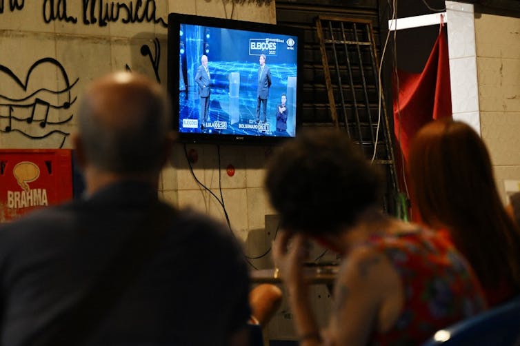 Des personnes regardent le débat Bolsonaro-Lula dans un bar