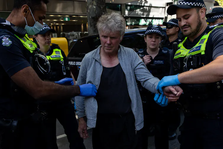 police hold a civilian by the arm