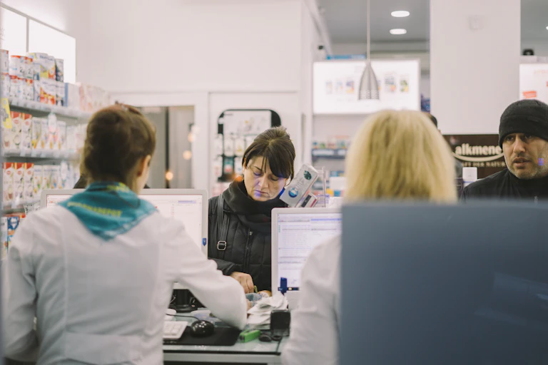 Two customers are served at a pharmacy counter