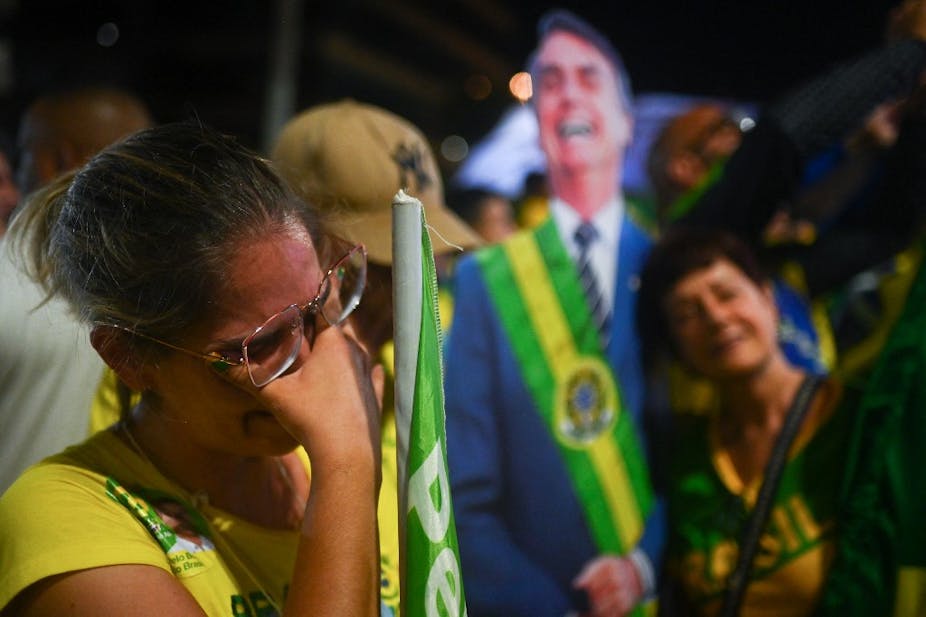 Une femme en larmes devant une représentation en carton de Jair Bolsonaro