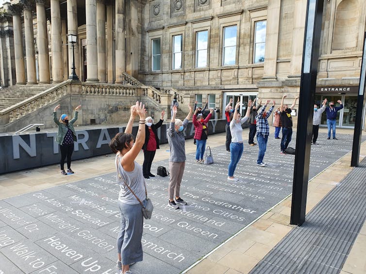 People practise a dance routing outside wearing masks