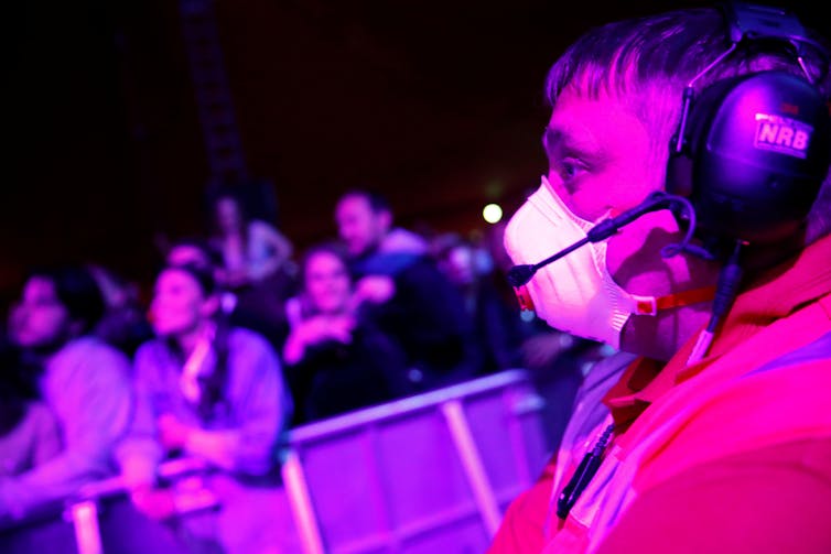 Security guard wearing mask with crowd behind