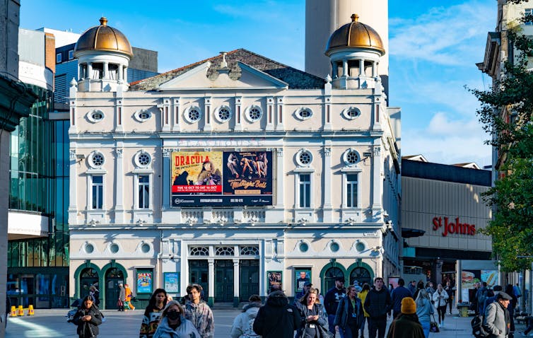 People walking in a square in front of a theatre