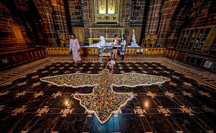 Girl adds a button to dove-shaped COVID memorial