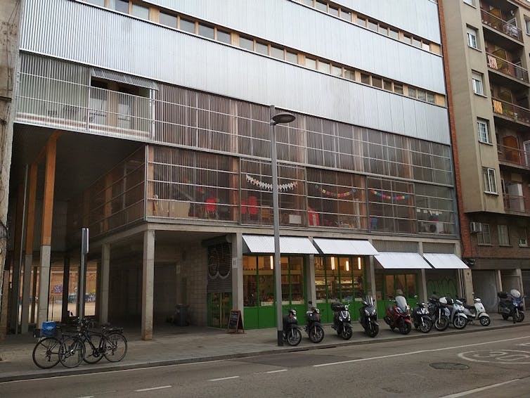A building facade with columns, large windows and bikes out front.