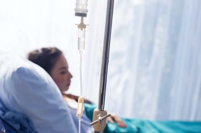 Mujer en una cama de hospital con tratamiento intravenoso.