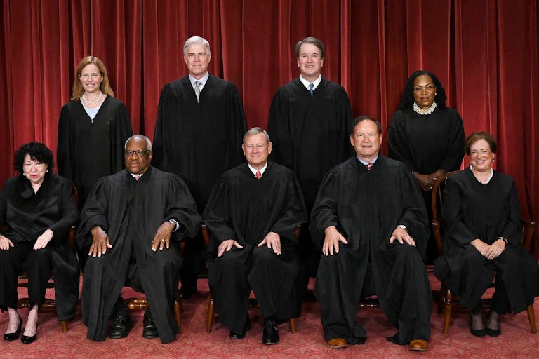 Five men and four women are dressed in black robes are seen posing for a group portrait.