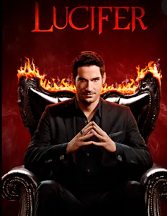 The figure of Lucifer looking like a human sitting in a leather armchair which is beginning to go up in flames.