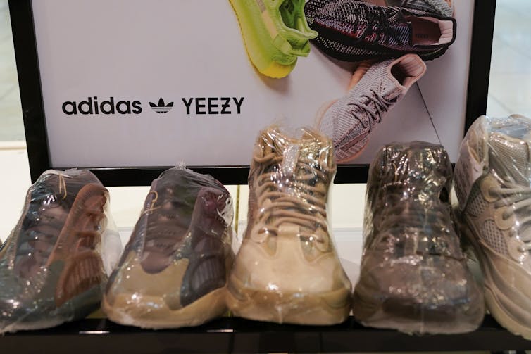 A sign for Adidas and Yeezy sits behind some shoes of various colors