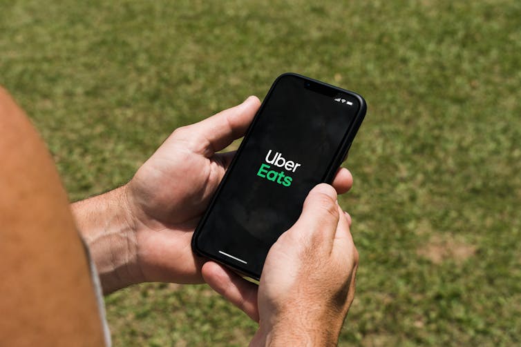 Hands holding a smartphone with the Uber Eats app loading screen visible on it