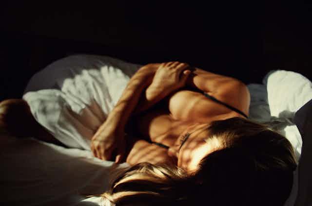 a woman in bed, looking sad, face turned away