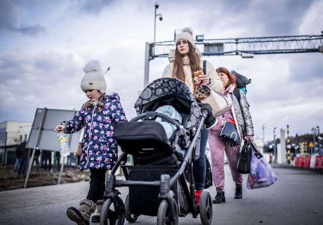 A Ukrainian woman with a baby in pushchair and another child walking beside her at the Polish border in February 2022.dren