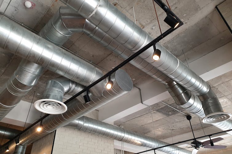 Silver ventilation pipes and vents criss-cross a ceiling.
