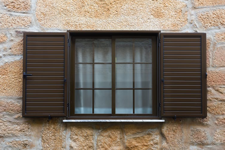 A window with open, brown shutters.