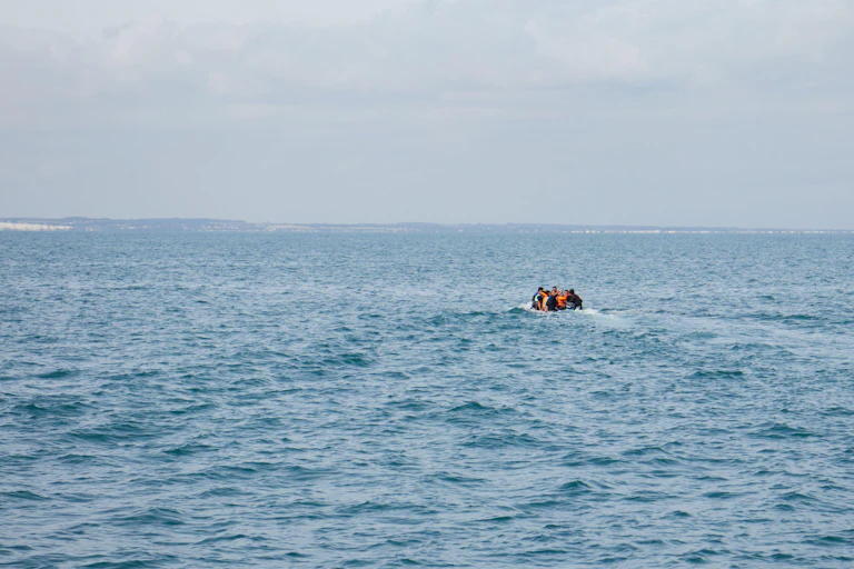 A small boat on a big open sea under a grey sky.