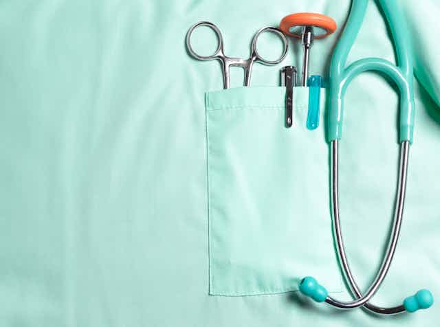Close up of chest pocket of medical scrubs, holding stethoscope and other medical tools.