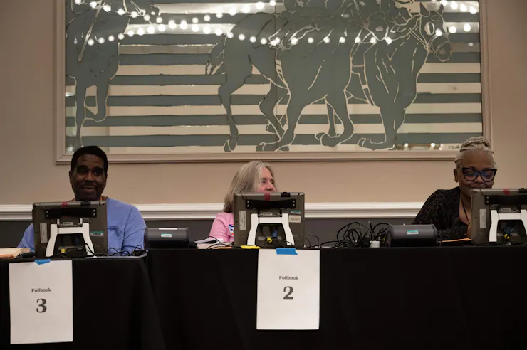 Three people sitting at computer screens at a table with a black tablecloth on it