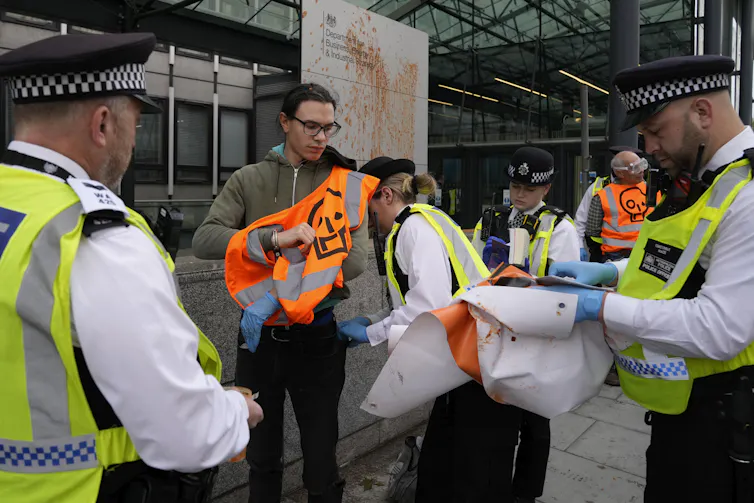 A sign seen dripping with red soup and police arresting a protestor.