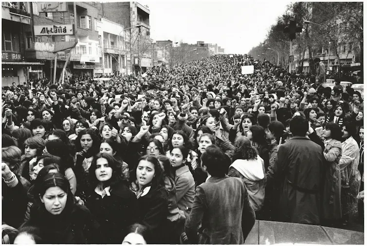 A black and white photo of a large group of women marching down a street.