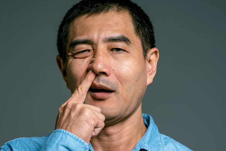 Man wearing blue denim shirt picking nose