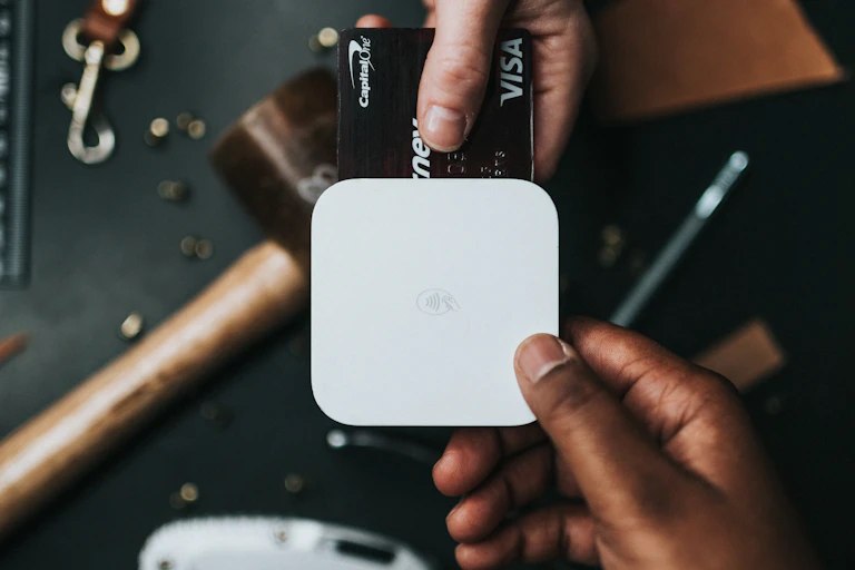 A photo of a person holding a credit card up to a reader.