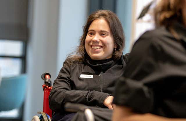 woman smiles, uses wheelchair