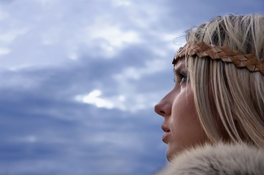 Blonde woman wearing furs looks up at a cloudy sky