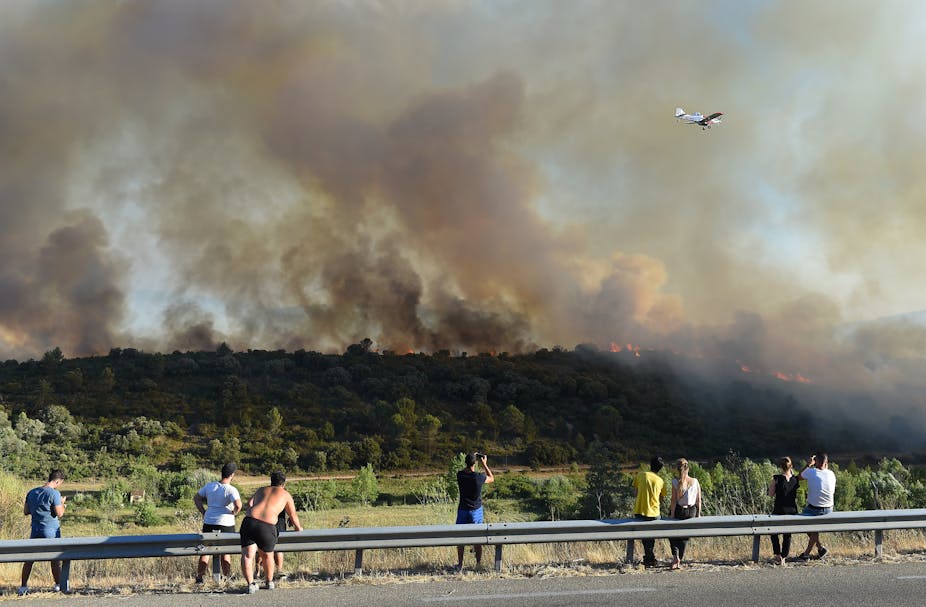 People watching a fire from a hilltop