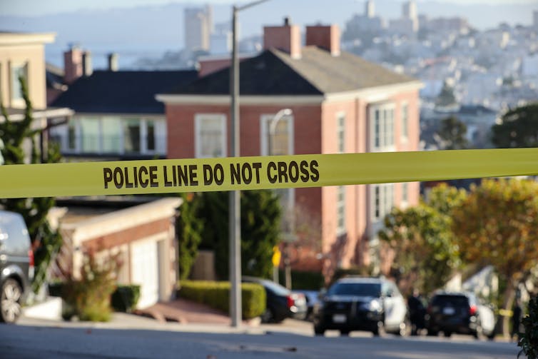 A large brick home down the hill from a police tape stretched across the street.