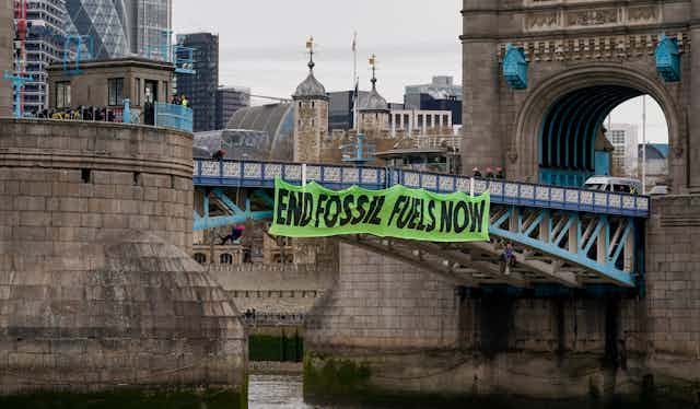 A banner saying "End fossil fuels now" hangs from Tower Bridge in London.