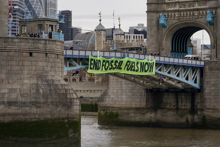 A banner saying "End fossil fuels now" hangs from Tower Bridge in London.