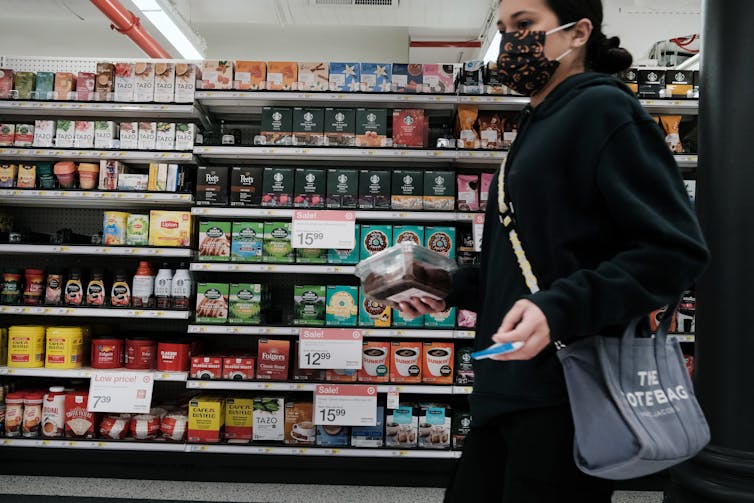 Se ve a una mujer comprando en una tienda de comestibles durante una época de inflación y precios más altos para la gasolina y los alimentos.